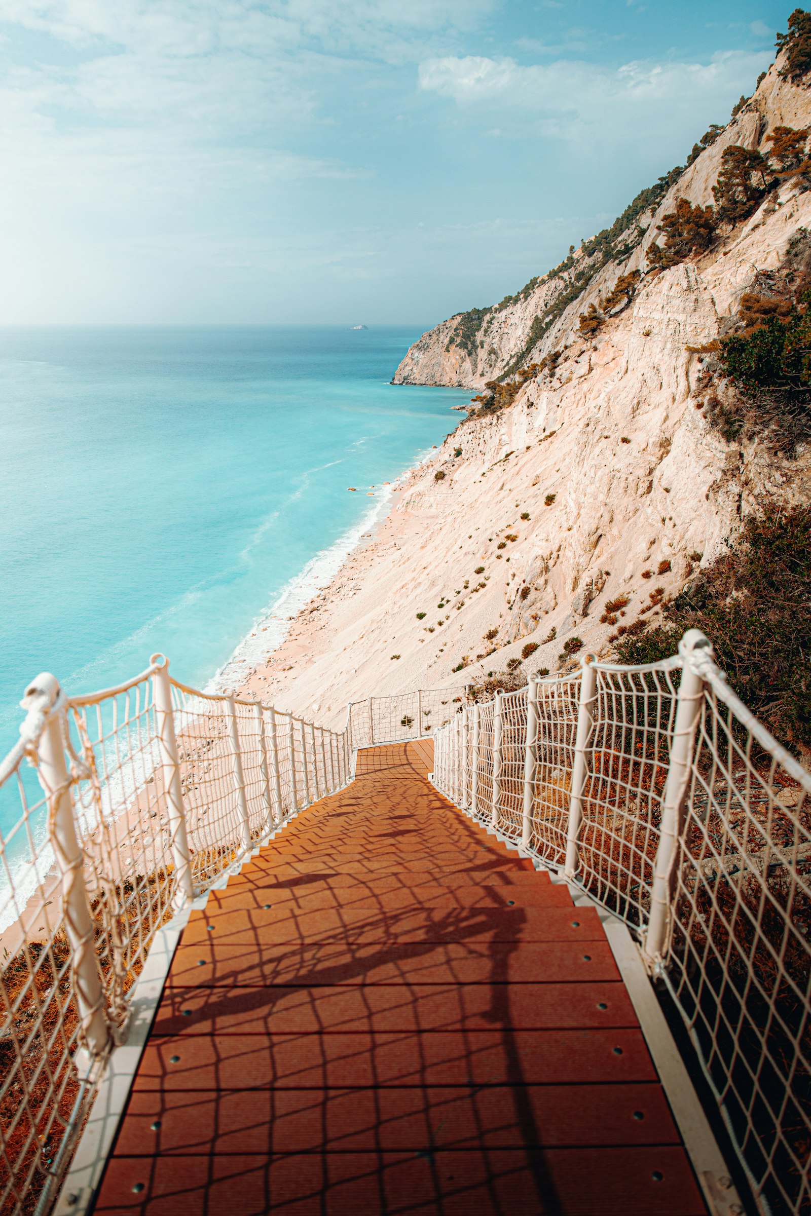 A staircase leading down to a beach along a turquoise coastline
